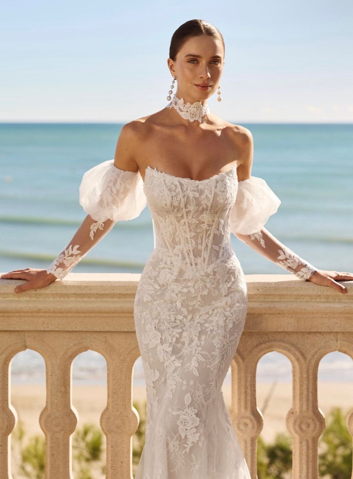A lace mermaid gown with detachable off-the-shoulder puff sleeves, by the sea