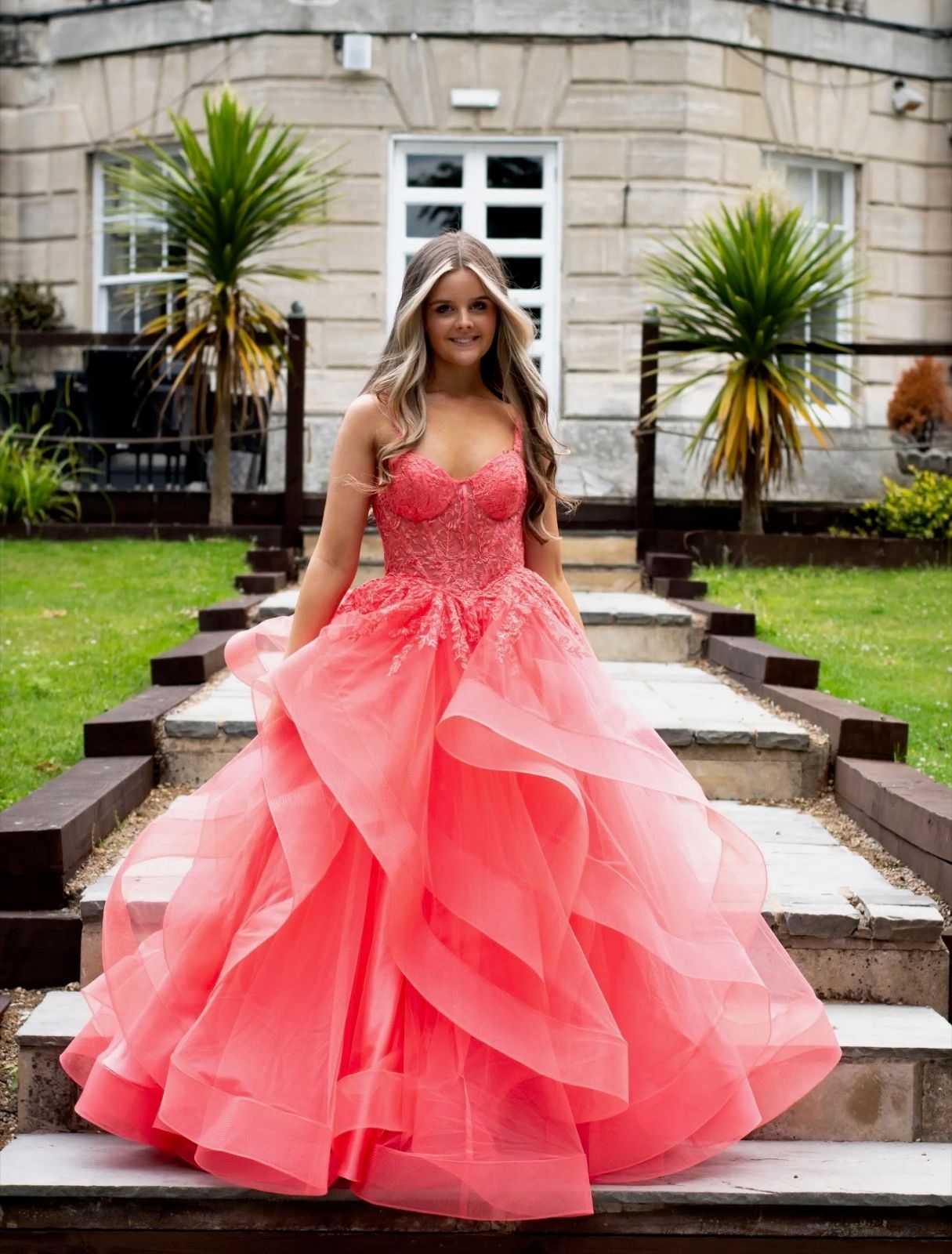 A coral prom dress with a corset bodice and tiered ruffle skirt